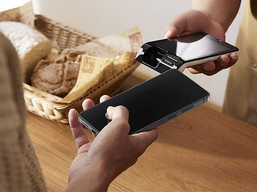 Person aligning a privacy screen protector over a smartphone while another phone is held nearby