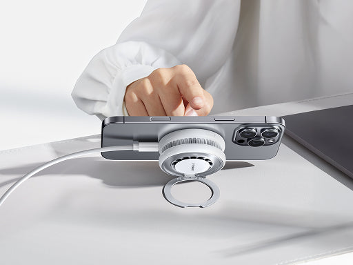 Smartphone on a desk with a magnetic charging stand and ring holder attached for hands-free use