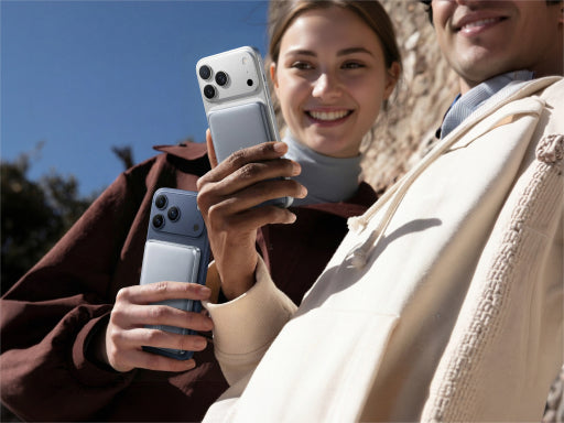 Two people holding smartphones with slim TORRAS magnetic power banks outdoors in a lifestyle scene