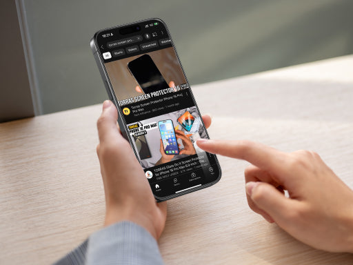 Person browsing TORRAS screen protector content on a smartphone held in both hands