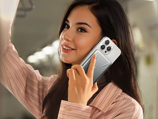 Smiling woman on a train talking on a white smartphone with a silver magnetic power bank attached to its back