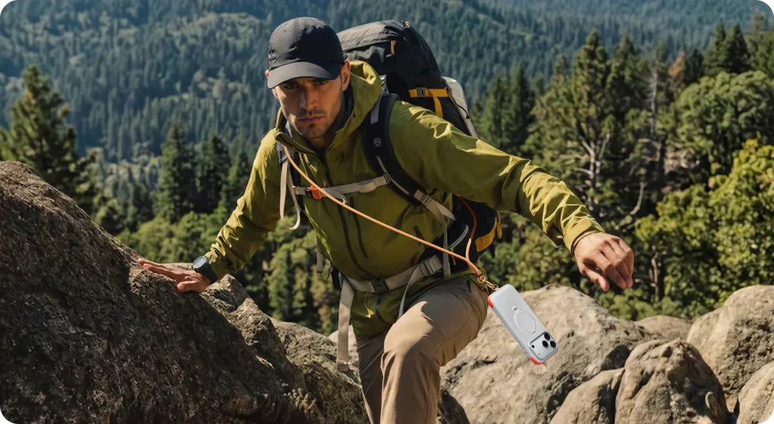 A hiker climbing a rocky trail with a phone secured by a crossbody lanyard.