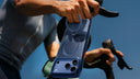 Person in a blue shirt mounting a dark phone on bicycle handlebars