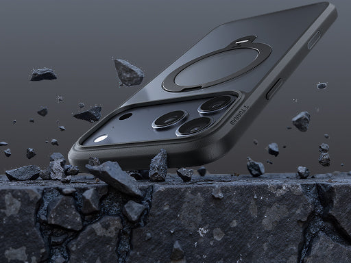 A rugged black smartphone case floating above a cracked stone surface with flying rock fragments