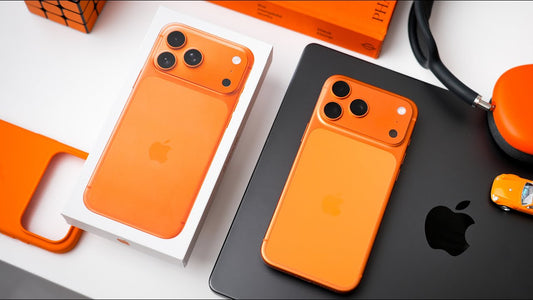 Orange iPhone on black tablet with matching box, headphones, case, toy car and cube