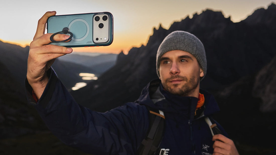 Man taking a mountain selfie with a blue TORRAS phone case featuring a foldable ring grip