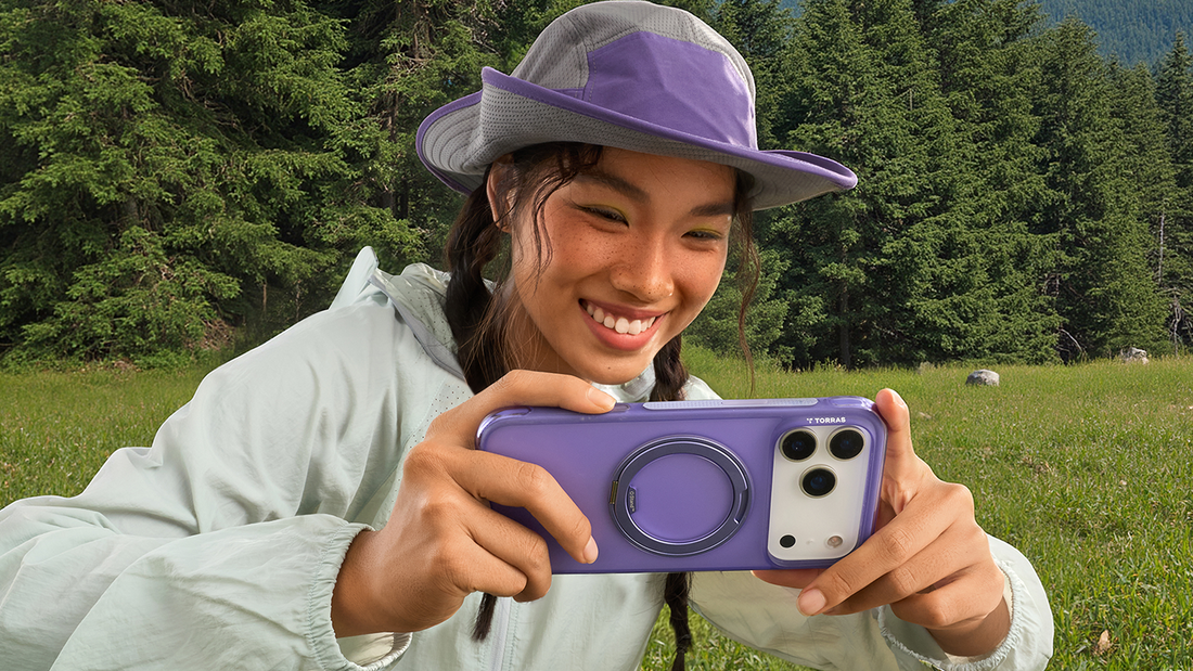 Smiling woman in a purple hat holding a purple phone with a built-in ring kickstand in a grassy field