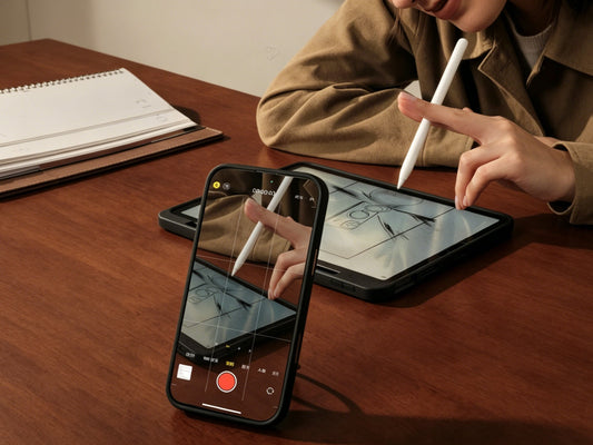 Phone recording a tablet sketching session on a desk with a stylus in use