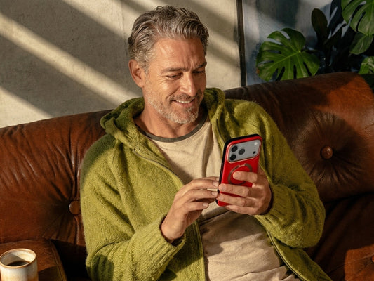 Person relaxing on a leather sofa while using a red phone case with ring grip