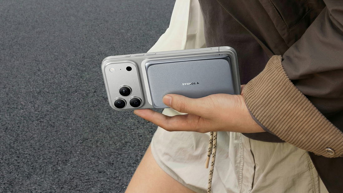 A person walking while holding a grey smartphone with a slim Torras magnetic power bank attached to the back