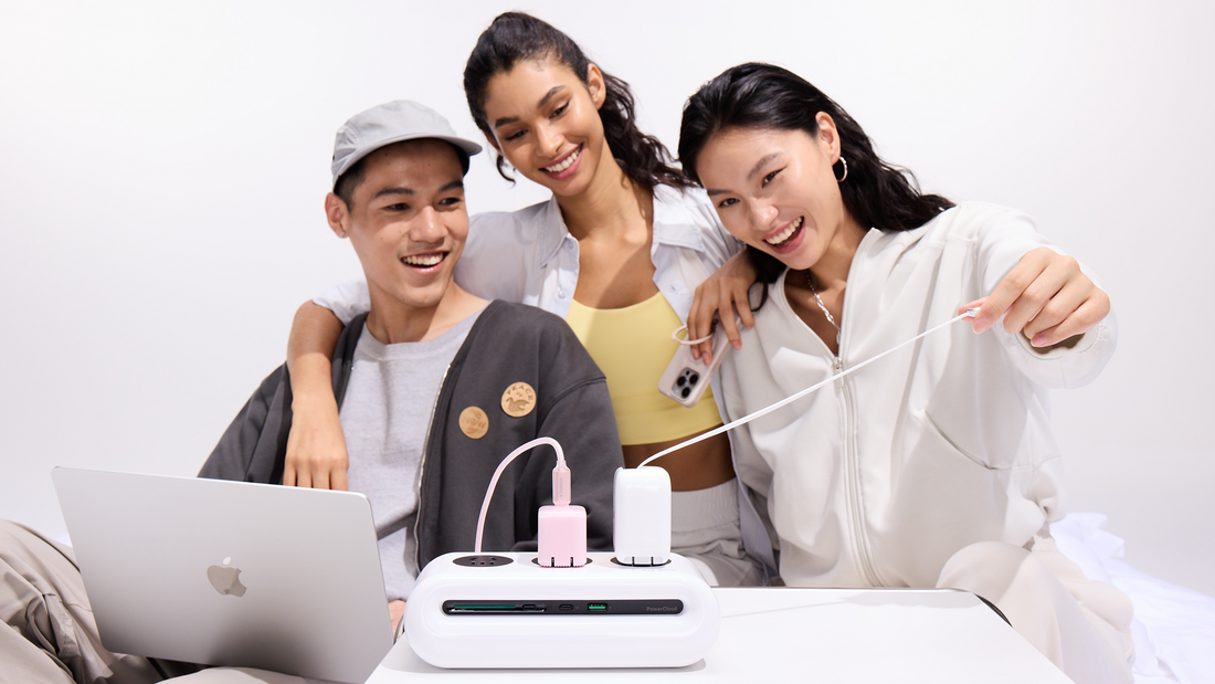 Three friends using a desktop charging station to power a laptop and mobile devices