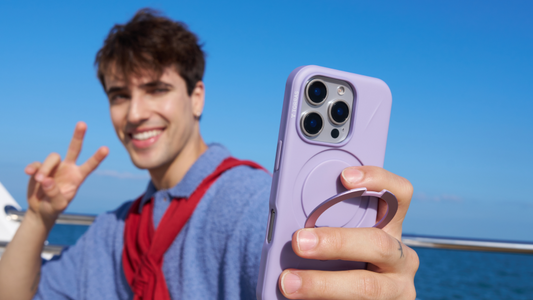 Man taking a selfie by the sea with a purple ring stand phone case