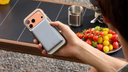 Hand holding an iPhone with a magnetic power bank near a plate of tomatoes