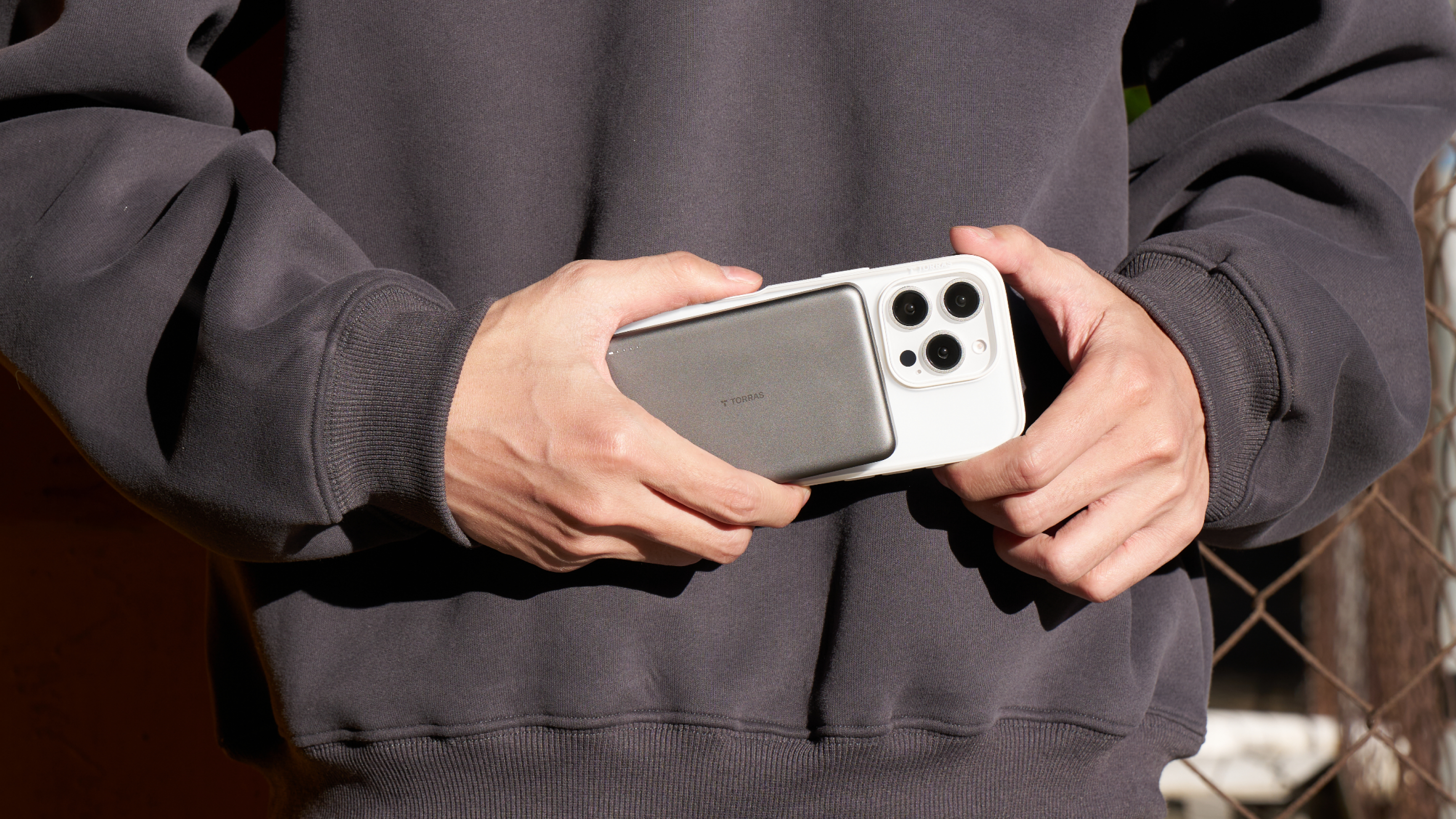 Person holding a white phone case with a magnetic power bank attached