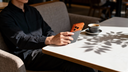 Person using a smartphone with a TORRAS phone case and stand at a cafe table
