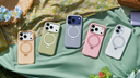 Five smartphones in colorful cases with built-in magnetic ring stands arranged on a picnic blanket