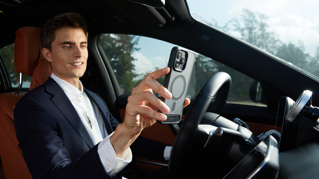 Man in a car holding a smartphone with a magnetic case near a dashboard phone mount