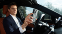 Man in a car holding a smartphone with a magnetic case near a dashboard phone mount