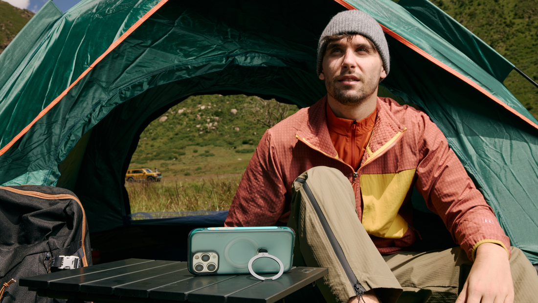 Camper sitting by a tent with a TORRAS phone case and circular stand on a folding table