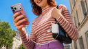 Woman using a pink TORRAS phone case while charging from a compact white portable charger outdoors