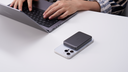 Dark gray TORRAS magnetic power bank attached to a white phone beside a laptop