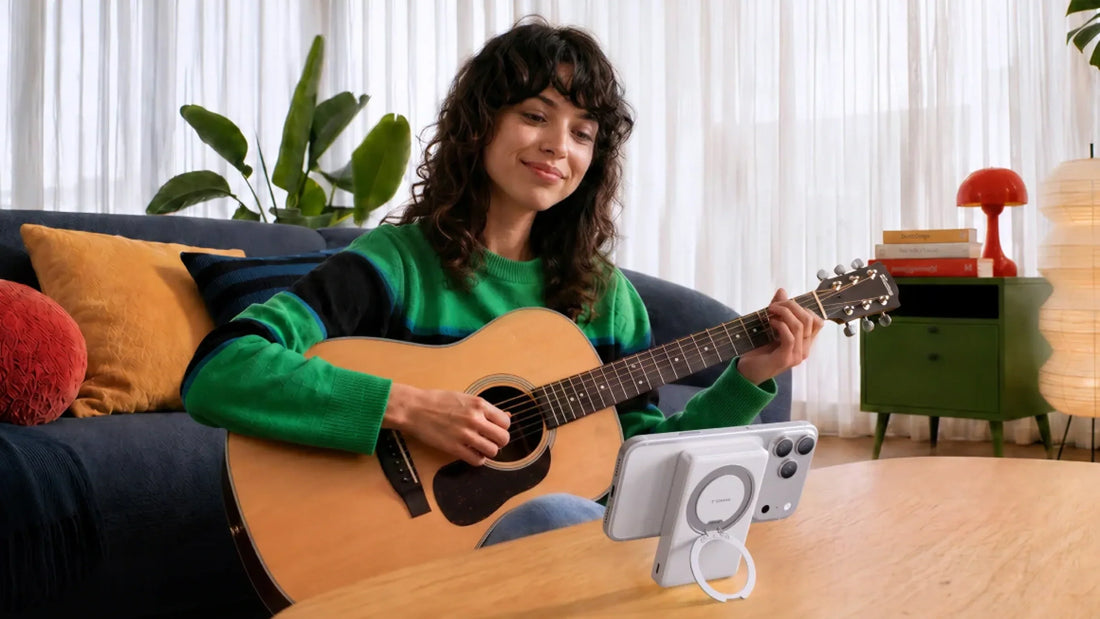 Woman playing guitar with her phone propped on a magnetic stand