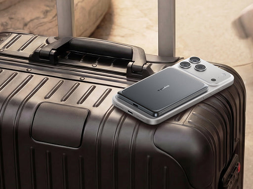 Slim magnetic phone accessory attached to a smartphone resting on a hard-shell suitcase during travel