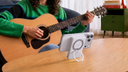Person playing guitar beside a smartphone supported by a circular stand on a table