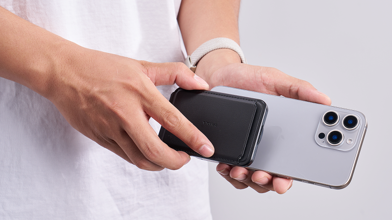 Hand attaching a magnetic wallet to the back of an iPhone