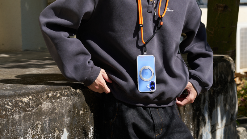 Person wearing a phone lanyard case over a dark hoodie outdoors