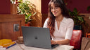 Woman working on a laptop at a cafe table by a window