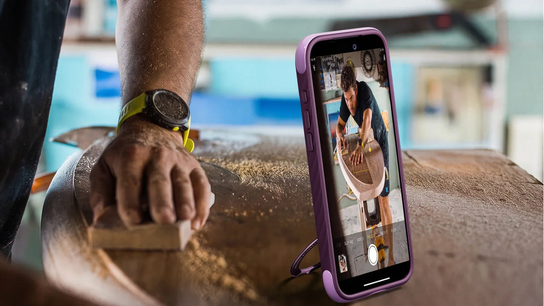 iPhone in a purple case propped on a potter bench while a craftsperson shapes clay