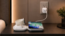 iPhone charging wirelessly on a bedside table beside an Apple Watch charging dock