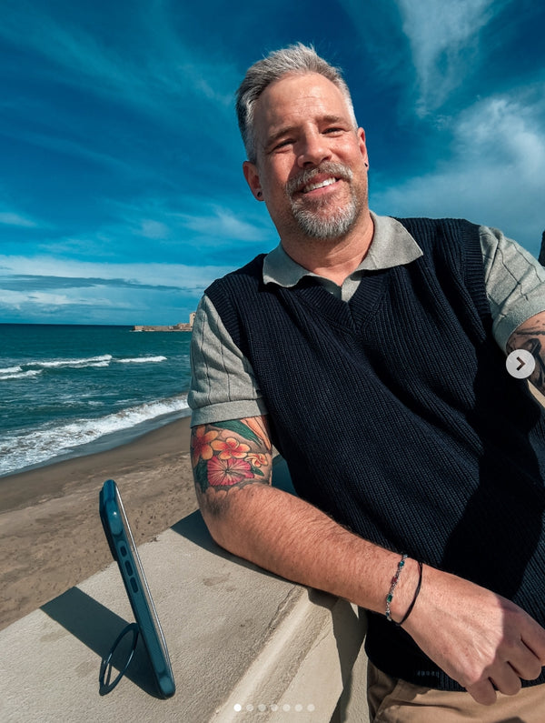 Man photographed by a phone propped on its stand by the sea