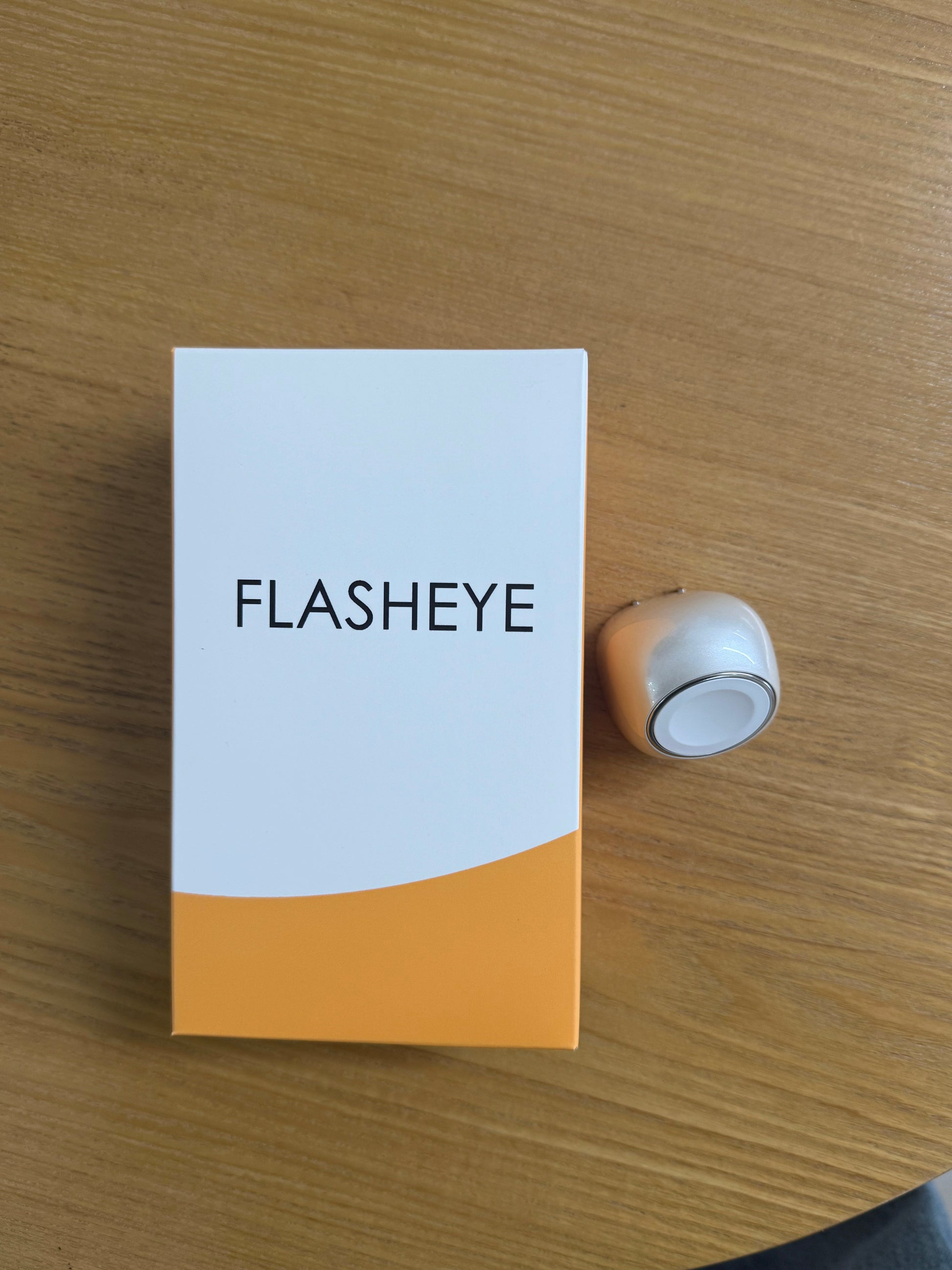 FLASHEYE Wireless Charger product box and silver accessory on wood