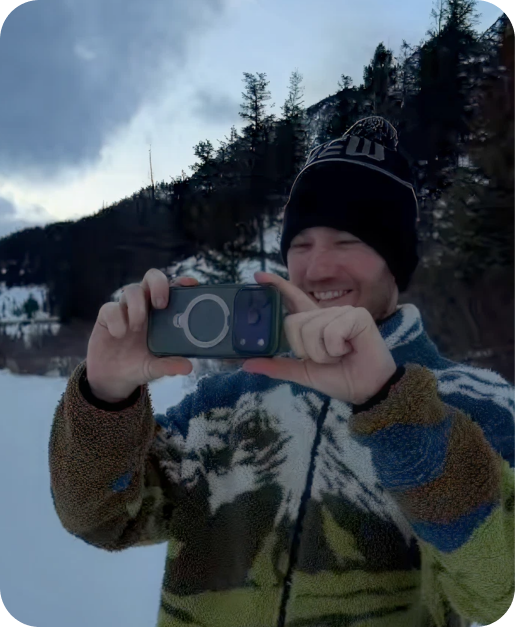 Man photographing a mountain lake with a phone in a TORRAS case